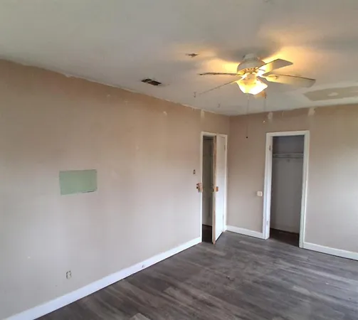 a view of an empty room with a window and wooden floor