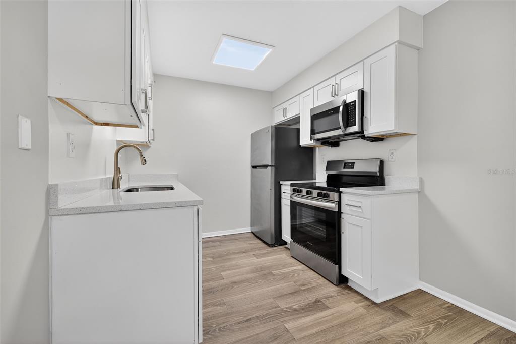 612 Bass Court, Unit 620B Dunedin, FL 34698 - Photo 9 of 32 a kitchen with stainless steel appliances a sink dishwasher a refrigerator and a stove top oven with wooden floor