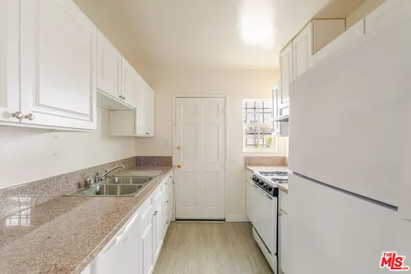 a kitchen with granite countertop a sink stove and cabinets