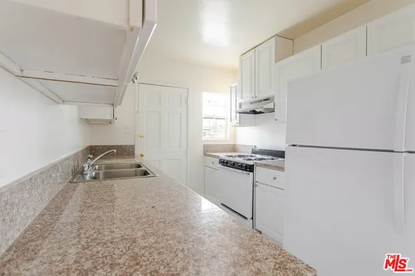 a kitchen with granite countertop a sink stove and refrigerator