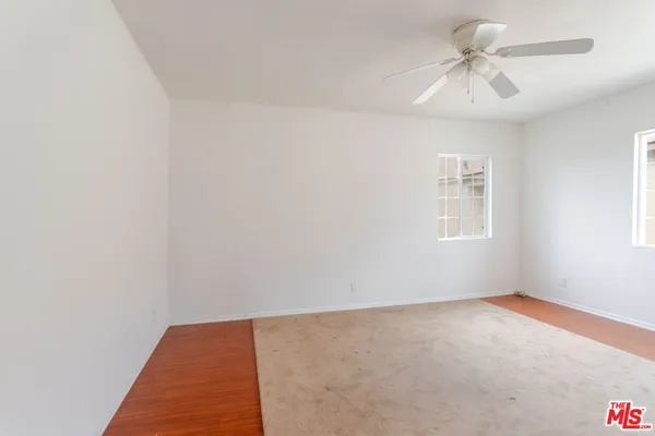 an empty room with windows and fan