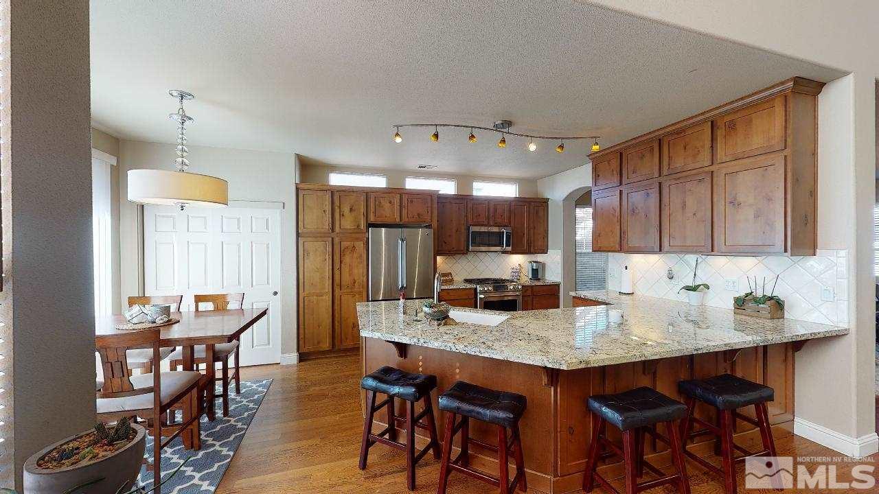 9565 Apache Rose Drive Reno, NV 89521 - Photo 8 of 25 a kitchen with stainless steel appliances granite countertop a table chairs stove refrigerator and cabinets