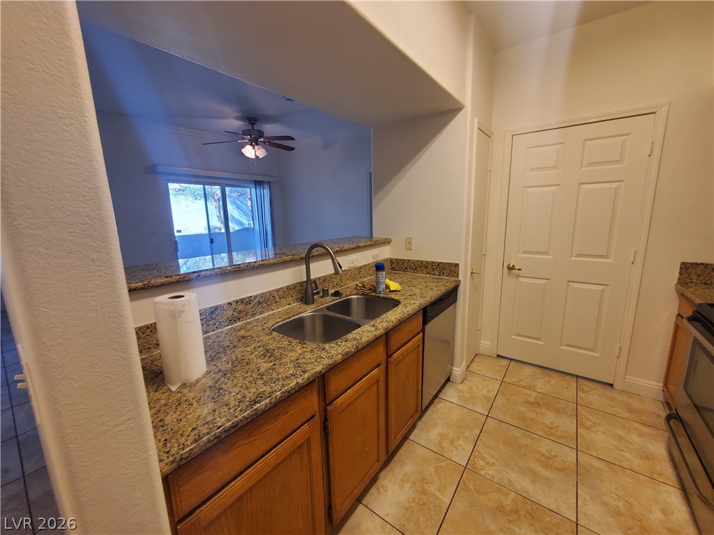 7255 West Sunset Road, Unit 1167 Las Vegas, NV 89113 - Photo 8 of 15 Kitchen featuring wood finish cabinetry, dark stone countertops, a ceiling fan, stainless steel appliances, and light tile patterned floors