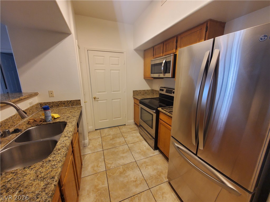7255 West Sunset Road, Unit 1167 Las Vegas, NV 89113 - Photo 9 of 15 Kitchen with stainless steel appliances, dark stone counters, wood finish cabinetry, and light tile patterned floors