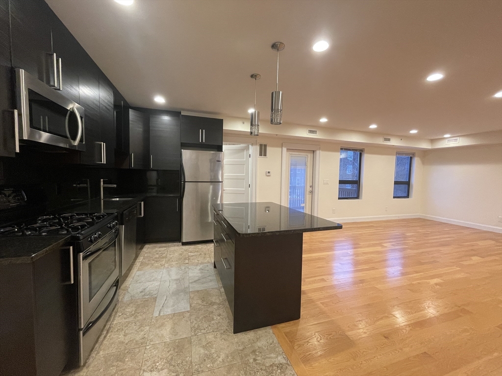a large kitchen with stainless steel appliances kitchen island granite countertop a large counter top and oven