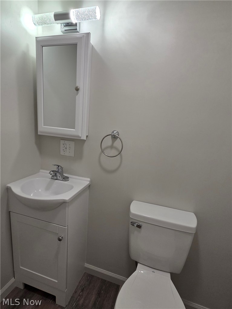 6145 Virginia Road Nashport, OH 43830 - Photo 15 of 24 Bathroom featuring a white vanity with integrated sink, chrome faucet, wall-mounted medicine cabinet, toilet, and wood-finish flooring