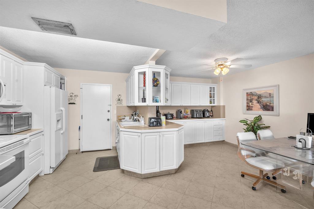 800 Northeast 195th Street, Unit 601 Miami, FL 33179 - Photo 11 of 35 a large white kitchen with cabinets and stainless steel appliances