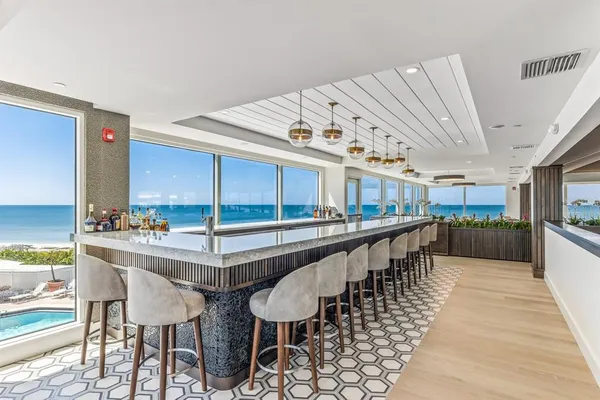 a dining hall with stainless steel appliances kitchen island granite countertop a table chairs and a large window