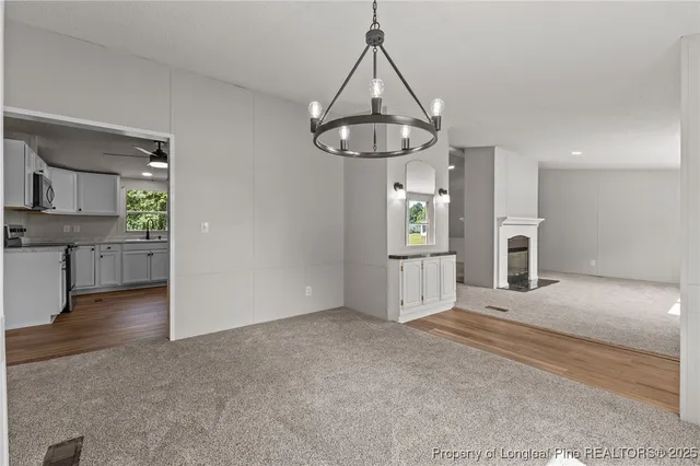 a view of a livingroom with a fireplace a ceiling fan and windows