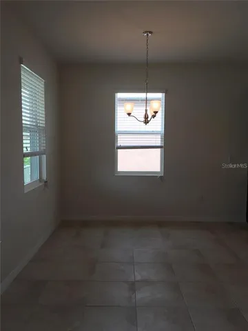 an empty room with chandelier fan and windows