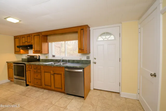 a kitchen with stainless steel appliances granite countertop a stove a sink and a refrigerator with wooden cabinets