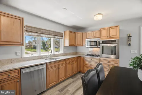 a kitchen with stainless steel appliances granite countertop a stove top oven a sink dishwasher a dining table and chairs with wooden floor