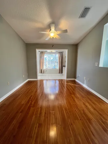 an empty room with wooden floor and windows