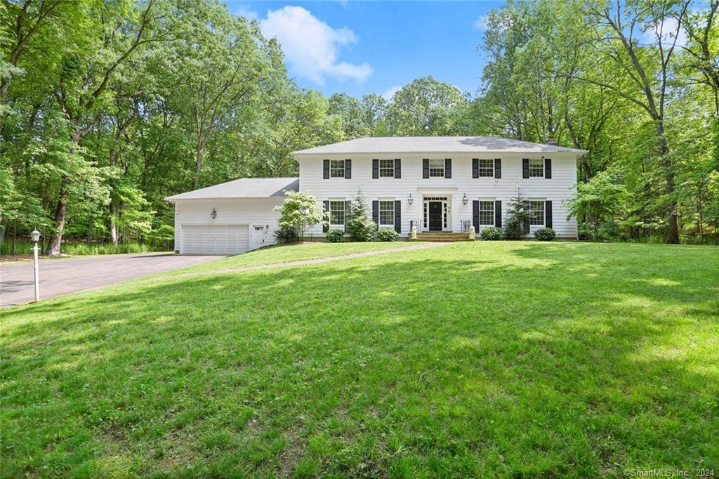 a view of a house with a big yard and large trees