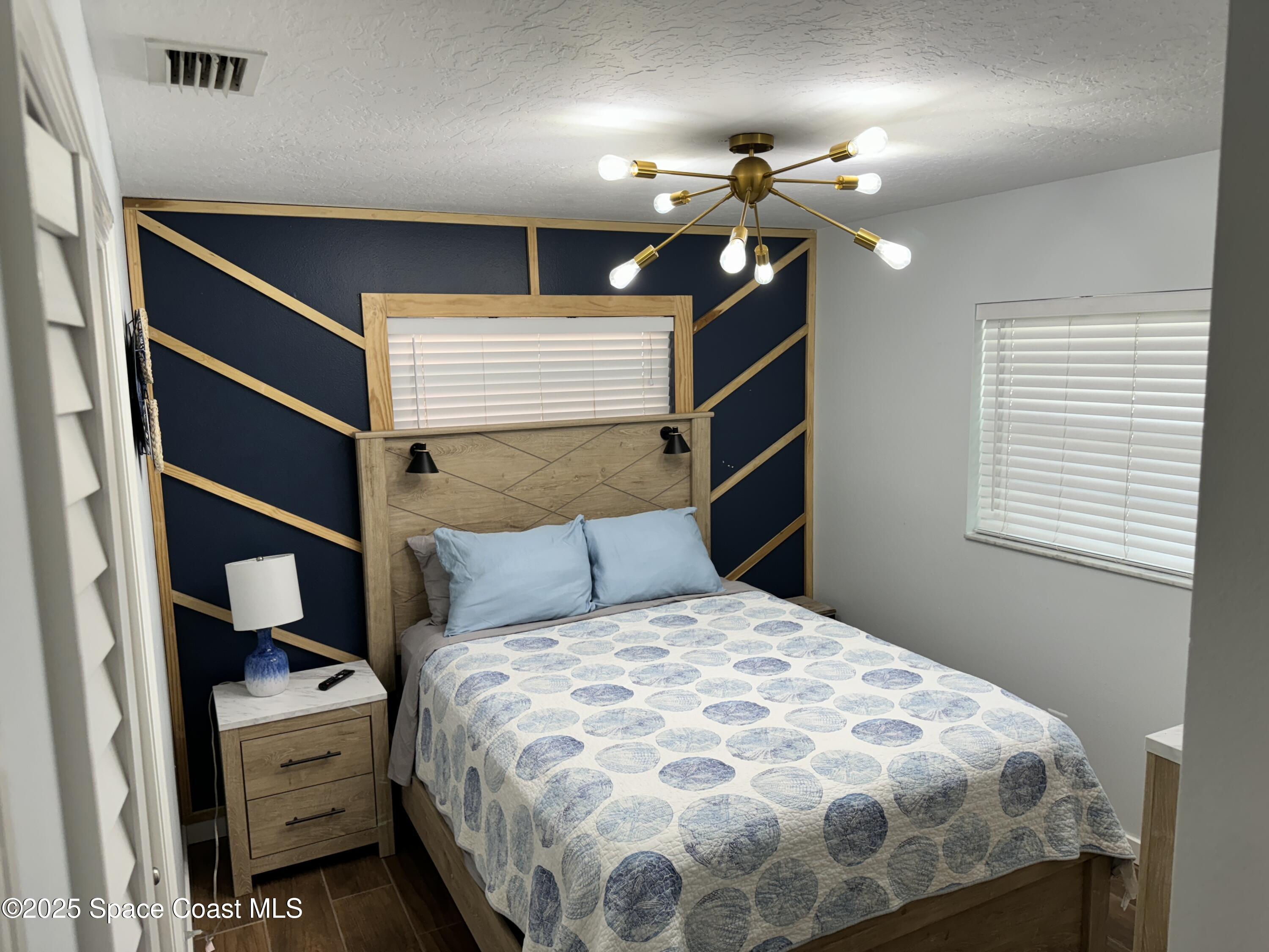 2130 South Patrick Drive Indian Harbour Beach, FL 32937 - Photo 12 of 14 a bedroom with a bed and a chandelier