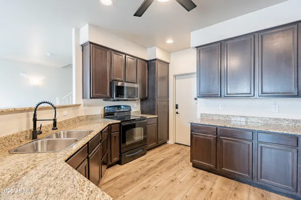 a kitchen with stainless steel appliances granite countertop a refrigerator a sink dishwasher a stove and a dining table with wooden floor
