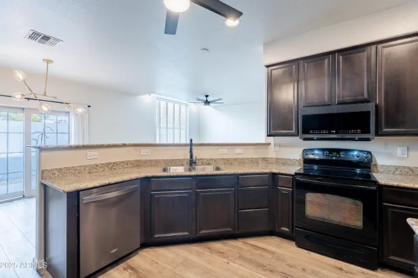 a kitchen with granite countertop stainless steel appliances wooden cabinets and a sink