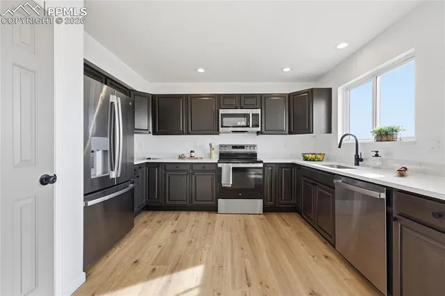 a kitchen with stainless steel appliances granite countertop a refrigerator a sink dishwasher a stove top oven a kitchen island and cabinets with wooden floor