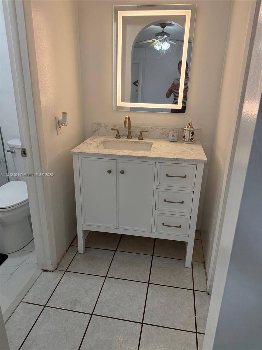 10661 Southwest 108th Avenue, Unit 2E Miami, FL 33176 - Photo 17 of 25 a bathroom with a granite countertop sink a mirror and a toilet