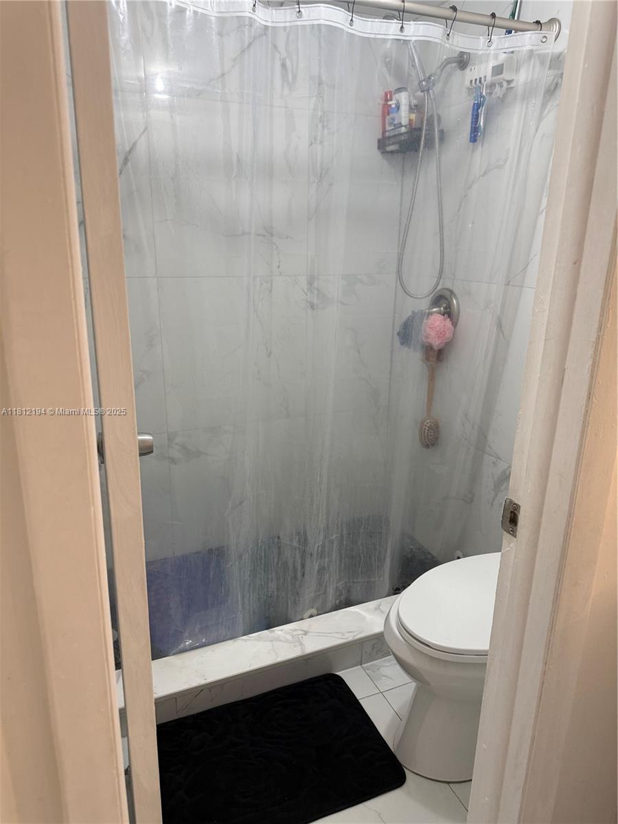 10661 Southwest 108th Avenue, Unit 2E Miami, FL 33176 - Photo 18 of 25 a bathroom with a granite countertop shower and a toilet