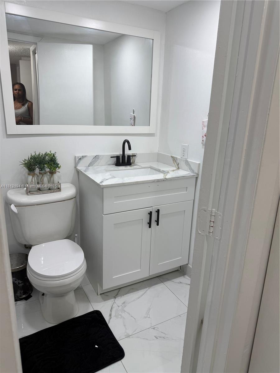 10661 Southwest 108th Avenue, Unit 2E Miami, FL 33176 - Photo 22 of 25 a bathroom with a sink toilet and a mirror
