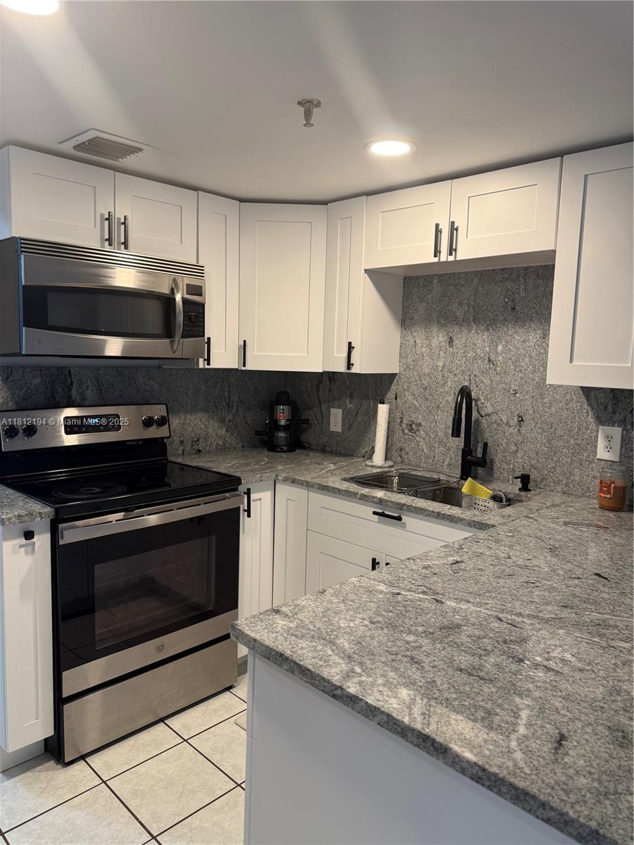 10661 Southwest 108th Avenue, Unit 2E Miami, FL 33176 - Photo 7 of 25 a kitchen with granite countertop a stove and a sink