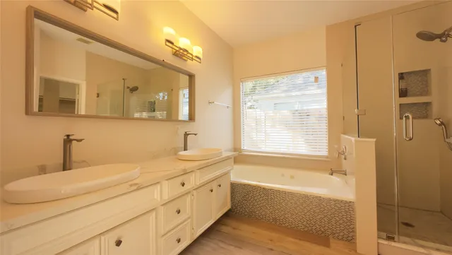 a bathroom with a granite countertop sink a mirror a bathtub and shower