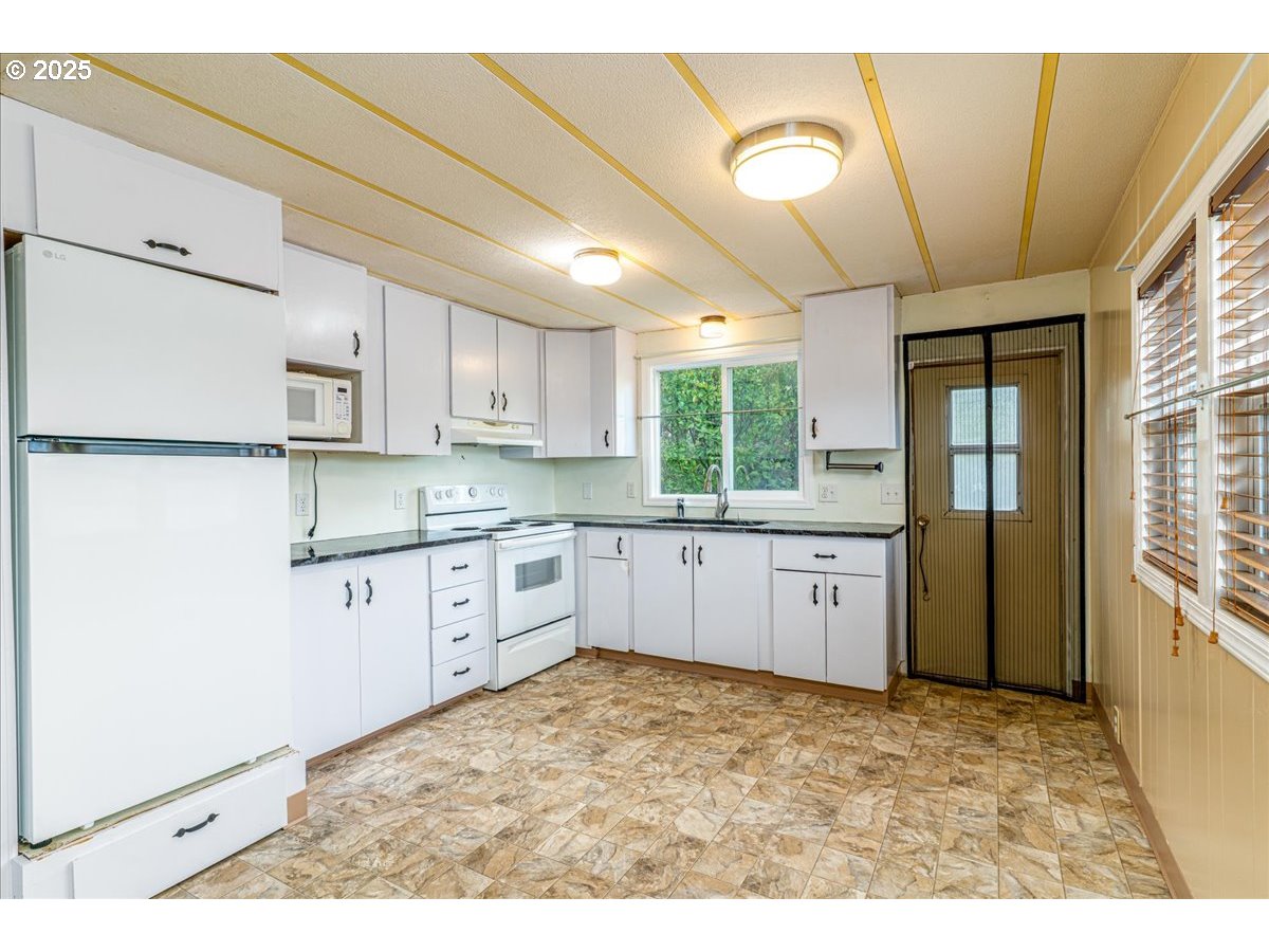 5510 Windsor Island Road North, Unit 19 Keizer, OR 97303 - Photo 12 of 32 a kitchen with granite countertop a refrigerator sink and cabinets