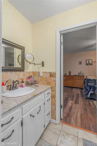 a en suite bathroom with a granite countertop sink and a mirror