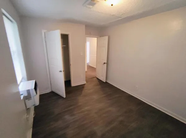 an empty room with wooden floor and windows