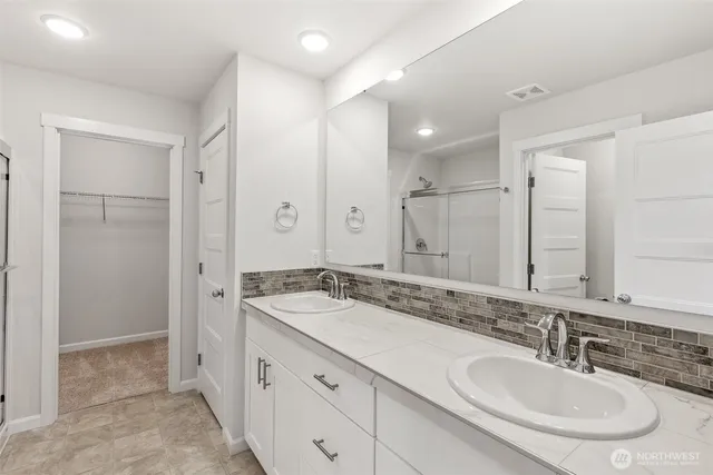 a bathroom with a sink double vanity granite tub shower and a mirror