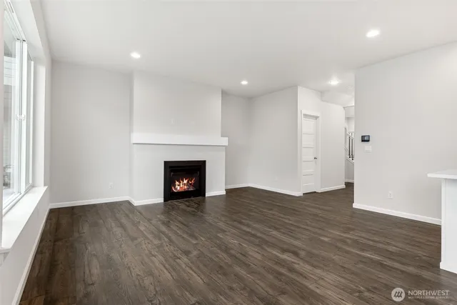 a view of an empty room with wooden floor fireplace and a window