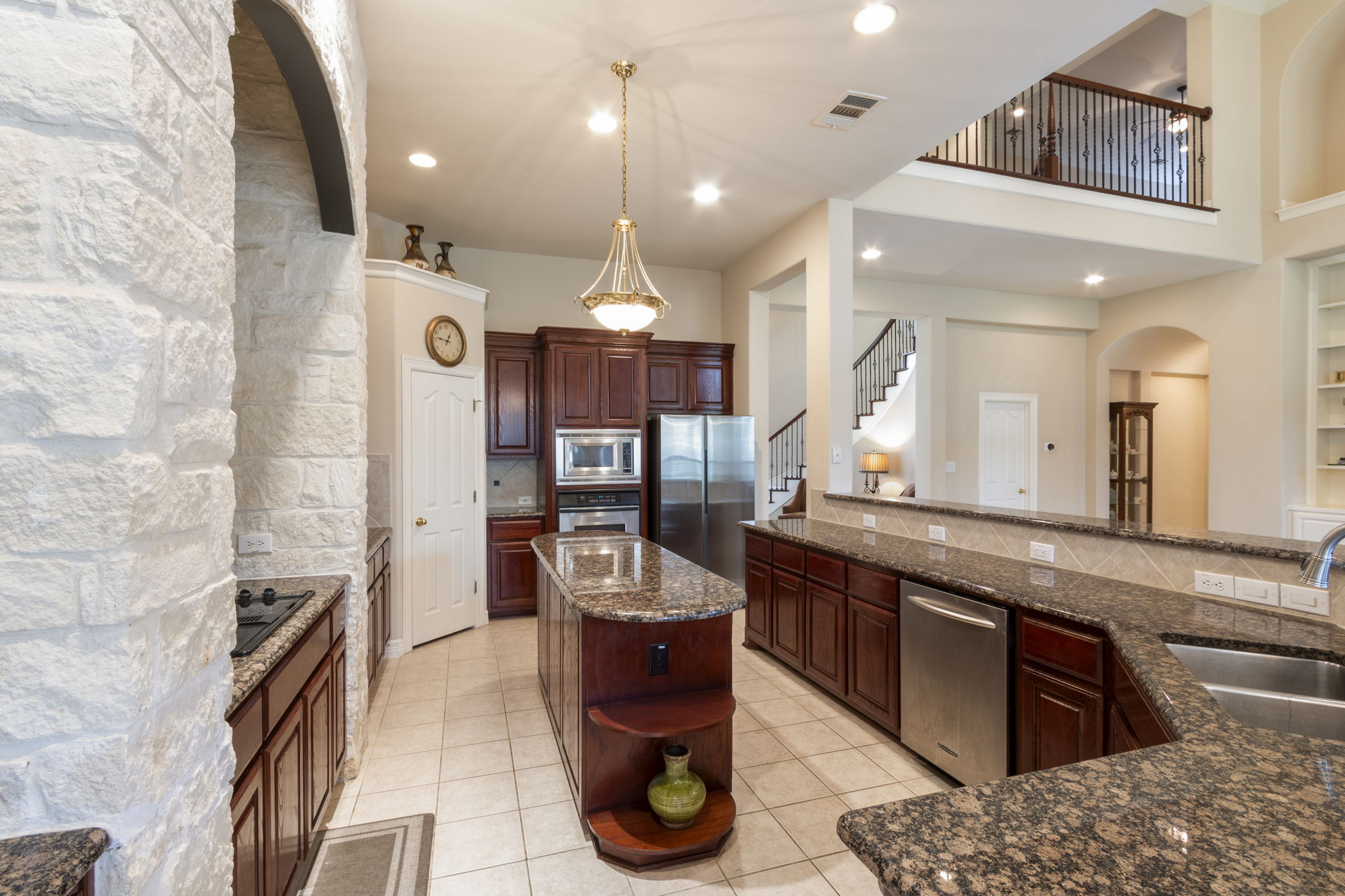 15 Sarazen Loop North Georgetown, TX 78628 - Photo 16 of 40 Kitchen with stainless steel appliances, a sink, open shelves, arched walkways, and dark stone countertops