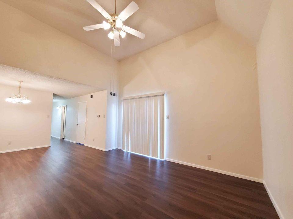 an empty room with wooden floor and a ceiling fan