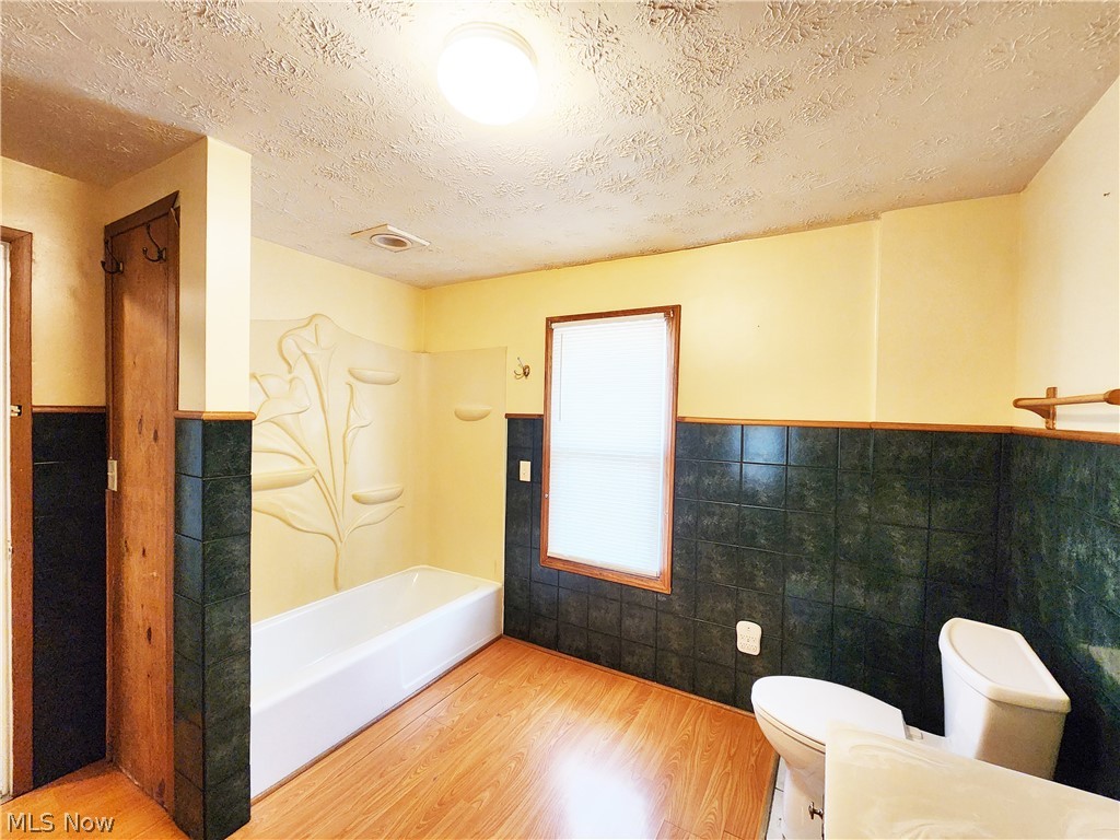 30 West Wilbeth Road, Unit A Akron, OH 44301 - Photo 12 of 16 Bathroom with wood-type flooring, tile walls, shower combination, toilet, and a textured ceiling