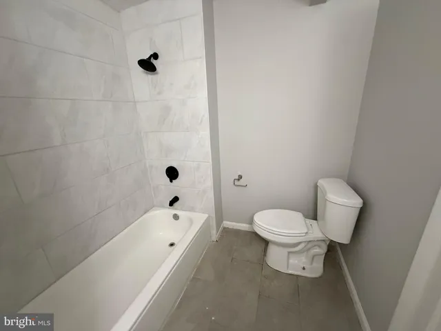 a bathroom with a toilet tub shower and mirror