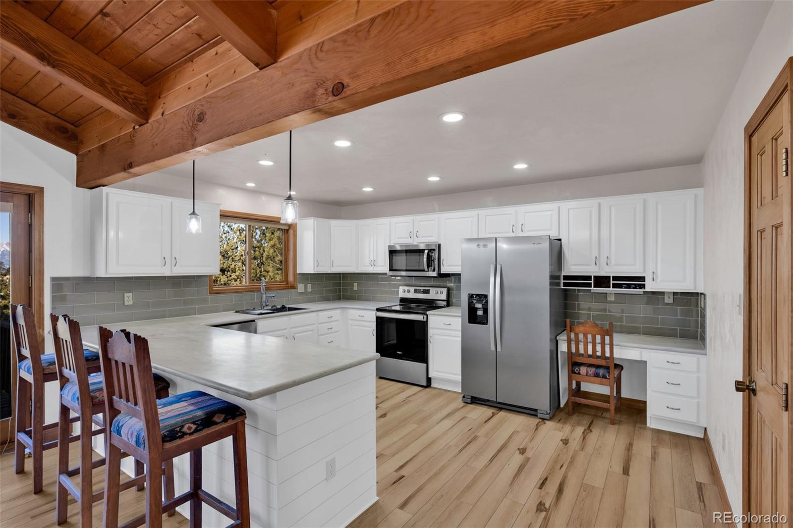 820 Schulze Ranch Road Westcliffe, CO 81252 - Photo 11 of 39 a kitchen with stainless steel appliances granite countertop a table chairs wooden floors and a view of living room