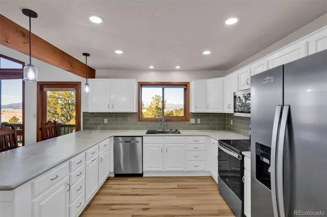 a kitchen with granite countertop white cabinets and black stainless steel appliances