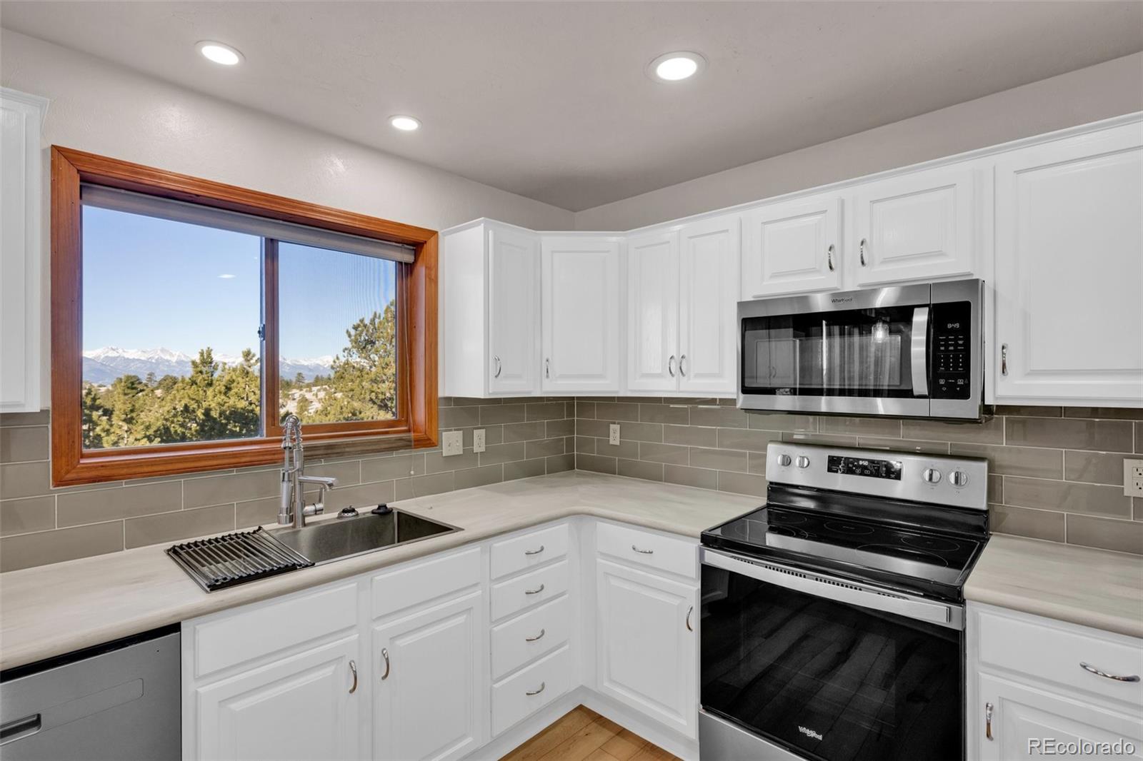 820 Schulze Ranch Road Westcliffe, CO 81252 - Photo 13 of 39 a kitchen with granite countertop white cabinets and black stainless steel appliances