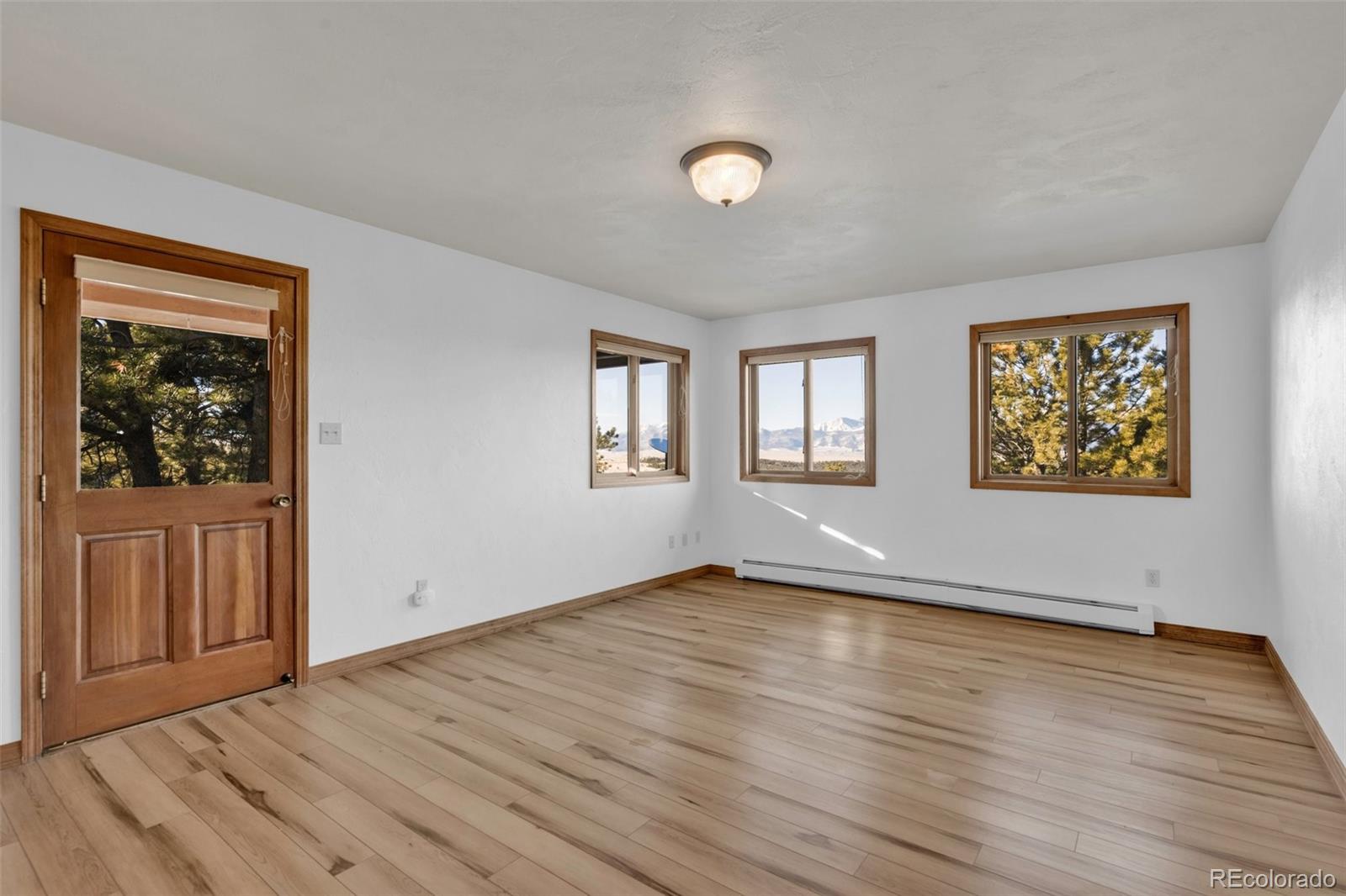 820 Schulze Ranch Road Westcliffe, CO 81252 - Photo 14 of 39 a view of an empty room with wooden floor and a window