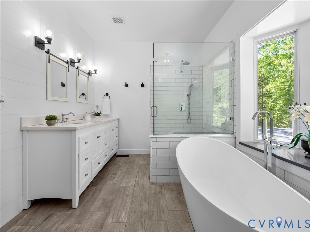 6126 Autumn Bluff Road Powhatan, VA 23139 - Photo 33 of 47 a spacious bathroom with a double vanity sink a large mirror a bathtub and next to a window