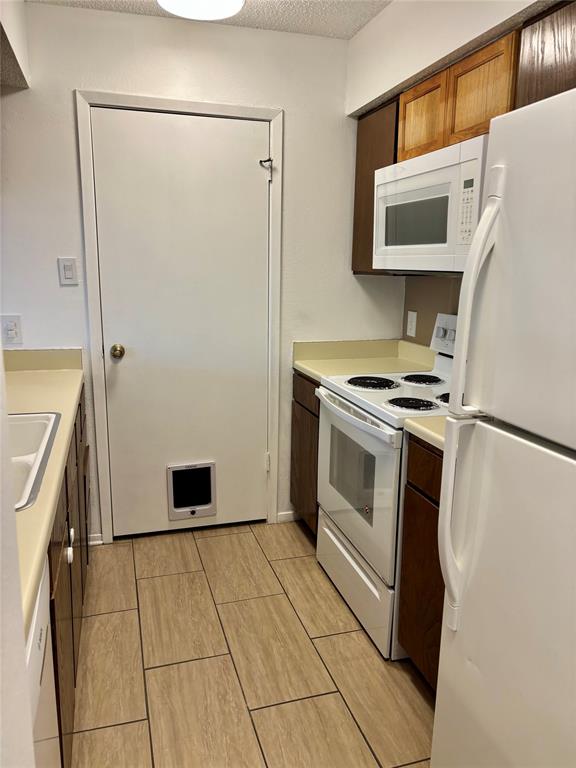 12480 Abrams Road, Unit 2805 Dallas, TX 75243 - Photo 13 of 18 Kitchen with white appliances, light countertops, and a textured ceiling