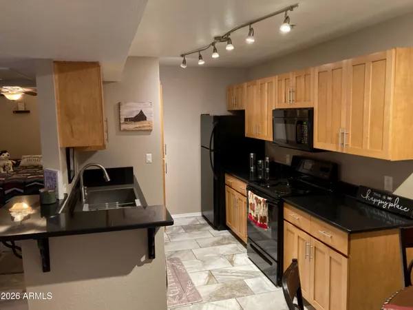 a kitchen with granite countertop a stove a sink and a refrigerator