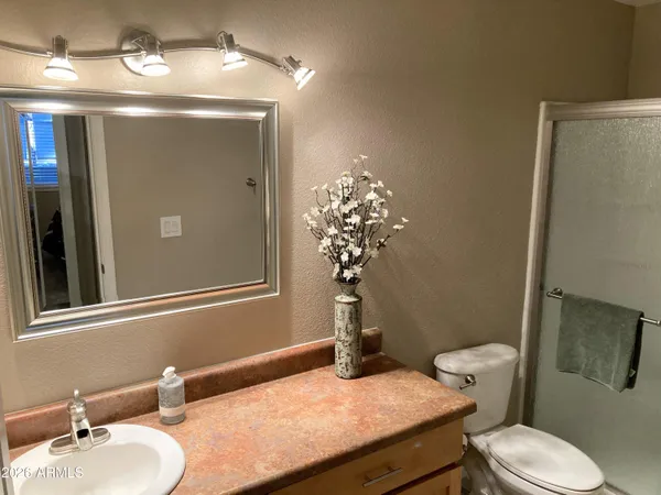 a bathroom with a sink vanity granite toilet and a mirror