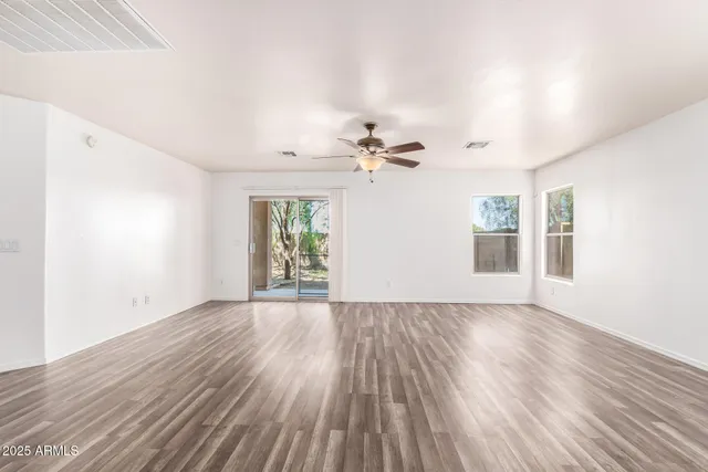 a view of an empty room with a window and wooden floor