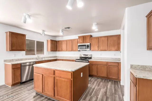 a kitchen with a stove a sink dishwasher a kitchen island with wooden cabinets and floor