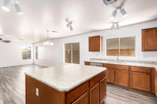 a kitchen with kitchen island a sink dishwasher and a stove with wooden floor