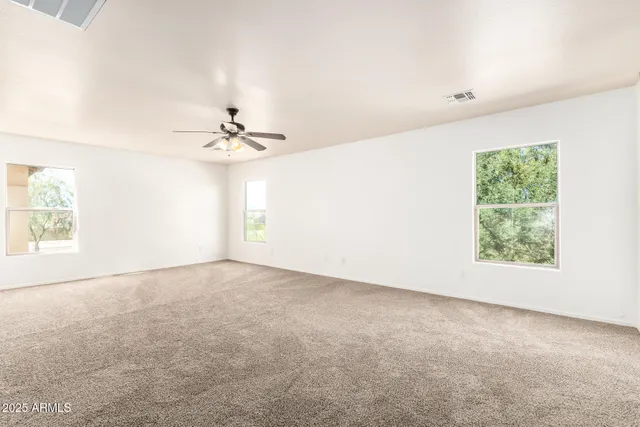 an empty room with windows and fan