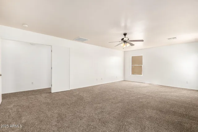 an empty room with windows and chandelier fan