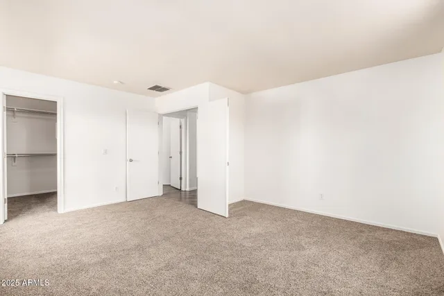 an empty room with a chandelier fan and windows